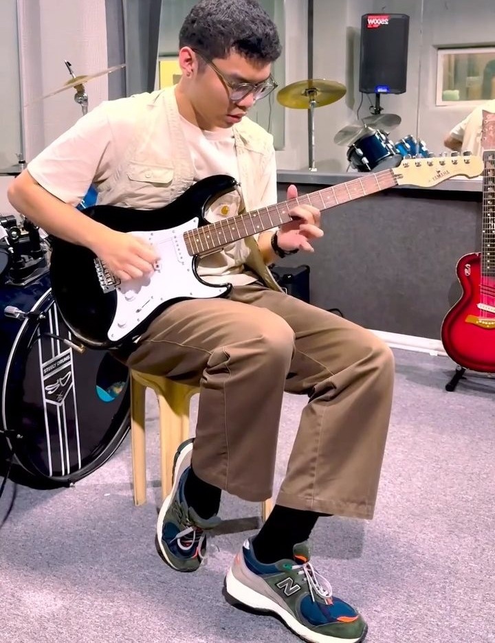 Student practicing electric guitar in the rehearsal room